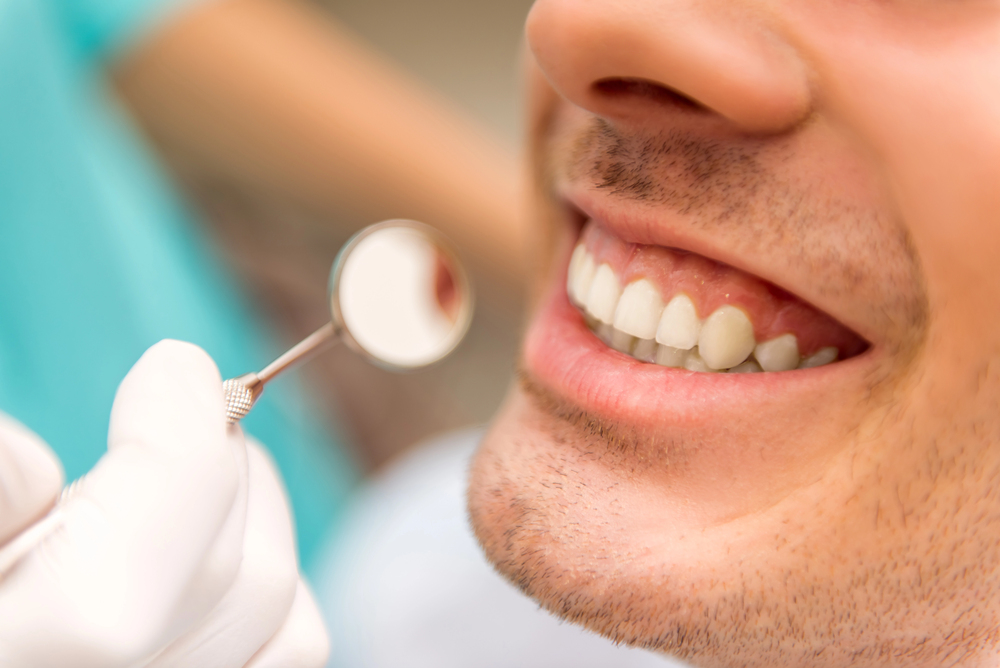 close up of man's teeth during dental cleaning & check Ups, dental mirror