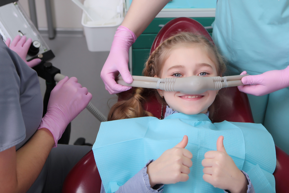 little girl with her thumbs up, undergoing sedation dentistry