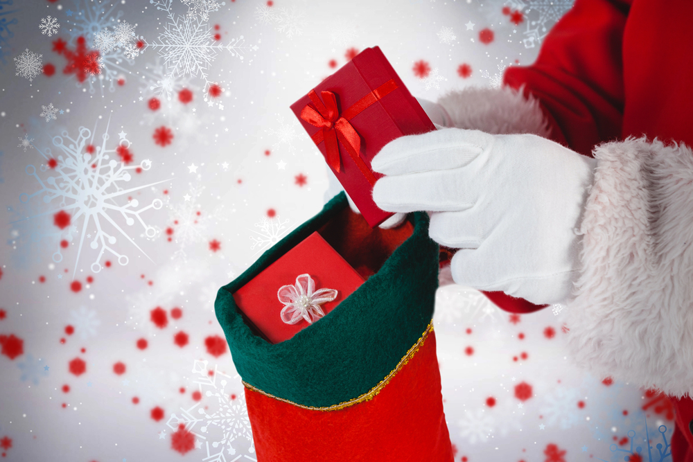 close up of Santa placing a red box gift into a red Christmas stocking