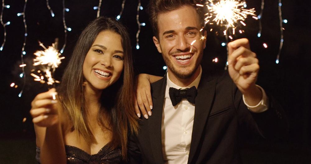 beautiful young couple holding sparklers at a new years eve party