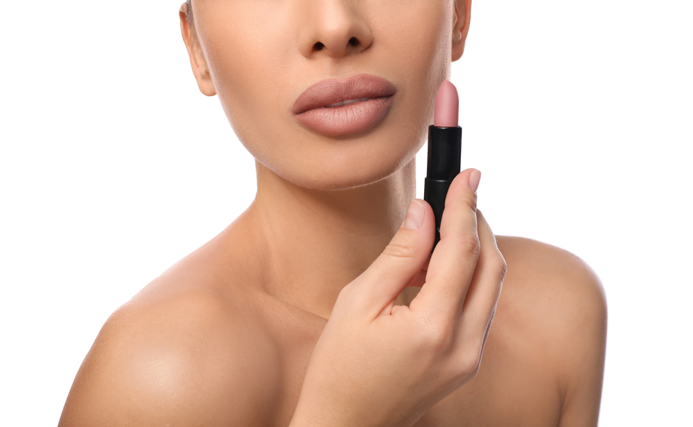 close up of woman holding lipstick up to her face